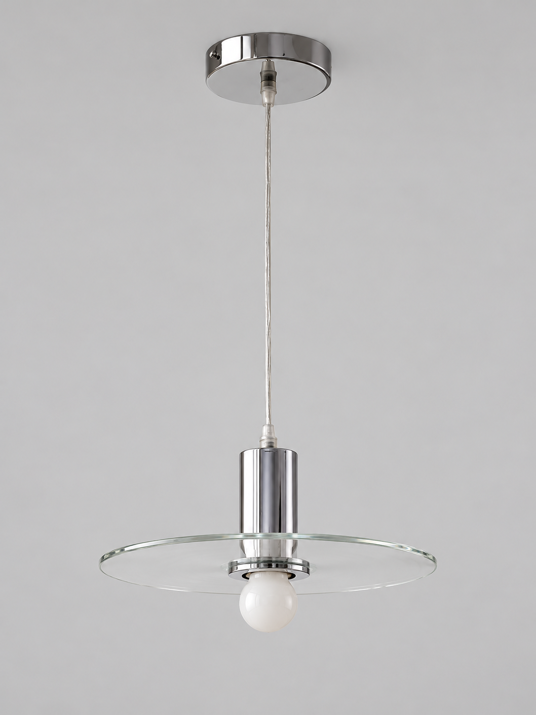 Clear glass disc pendant lamp with milky-white bulb finish and chrome-tone fittings, shown unlit