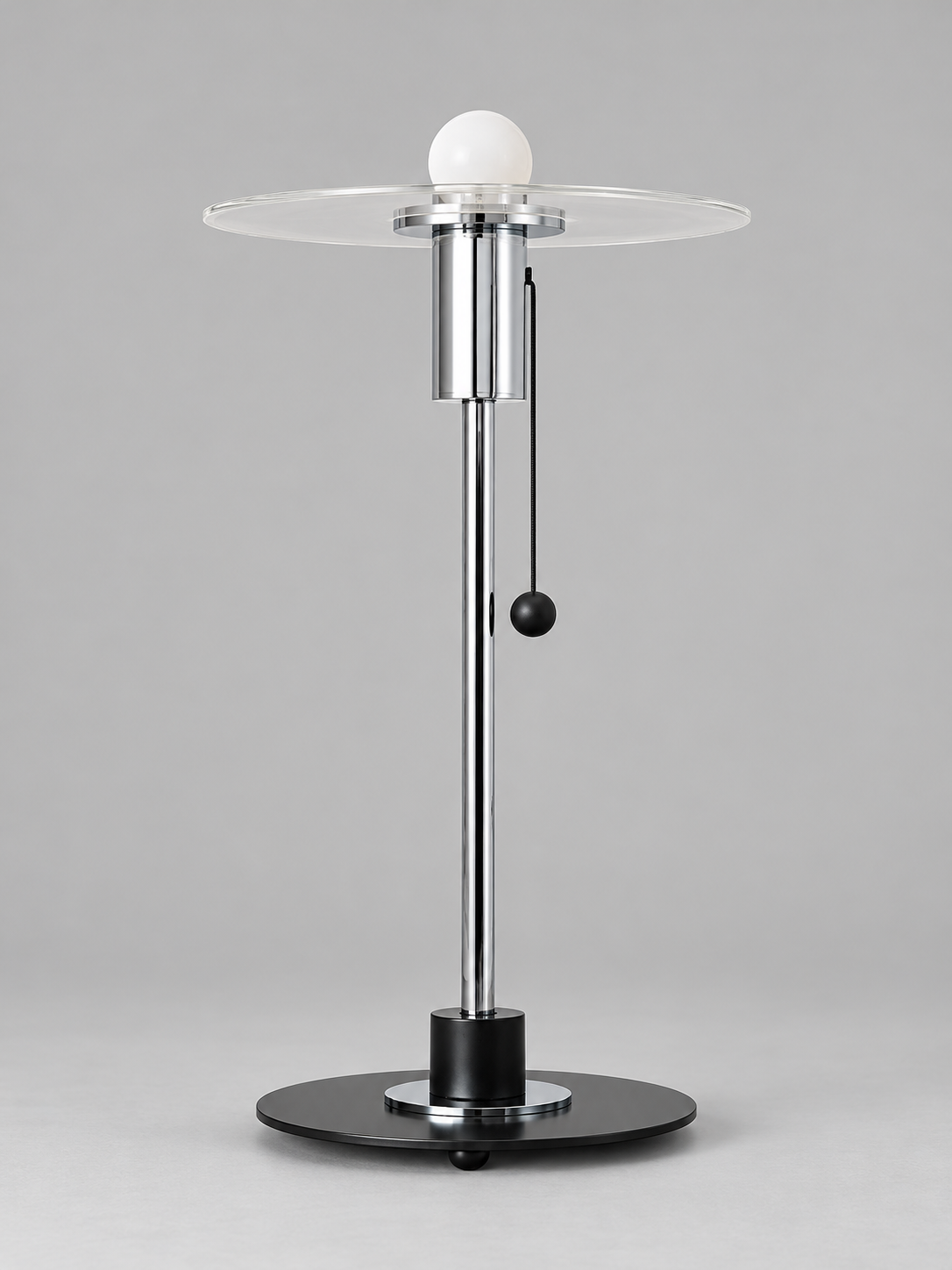 Clear glass disc table lamp with milky-white bulb finish and chrome-tone fittings, shown unlit