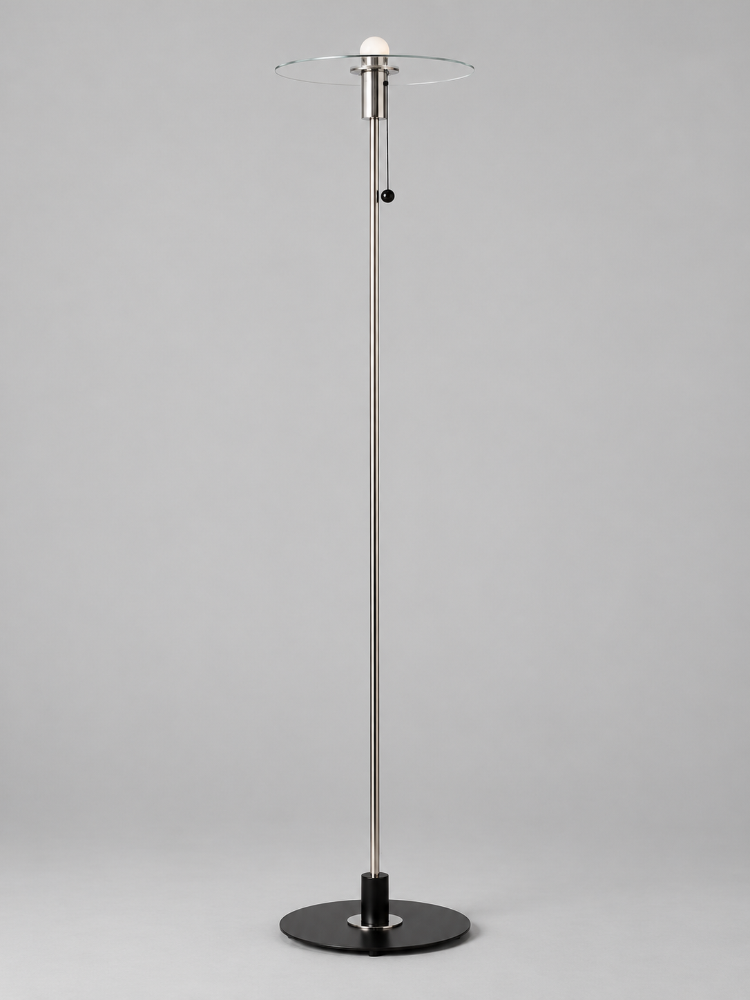 Clear glass disc floor lamp with milky-white bulb finish and chrome-tone fittings, shown unlit