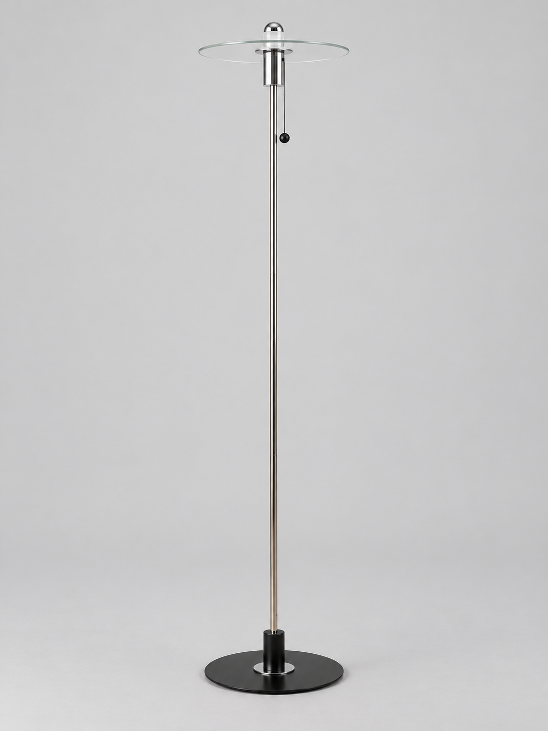 Clear glass disc floor lamp with half-chrome bulb finish and chrome-tone fittings, shown unlit