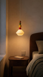 Memphis Bead Pendant casting warm light beside a bedside table