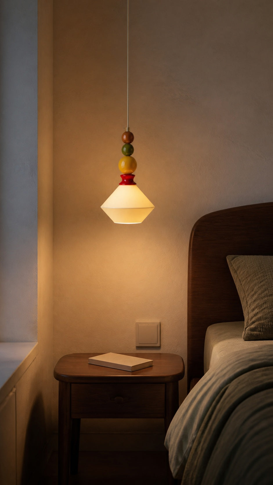 Memphis Bead Pendant casting warm light beside a bedside table