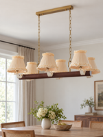 Linear 6-light chandelier with cream ruffled fabric shades, shown switched off in daylight