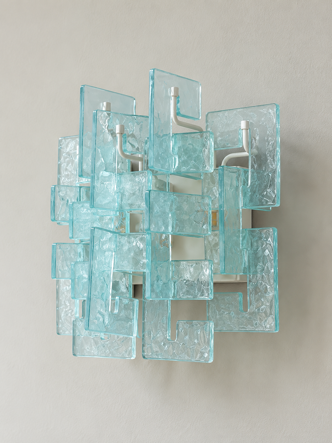 White wall sconce with blue textured glass panels, shown switched off in daylight