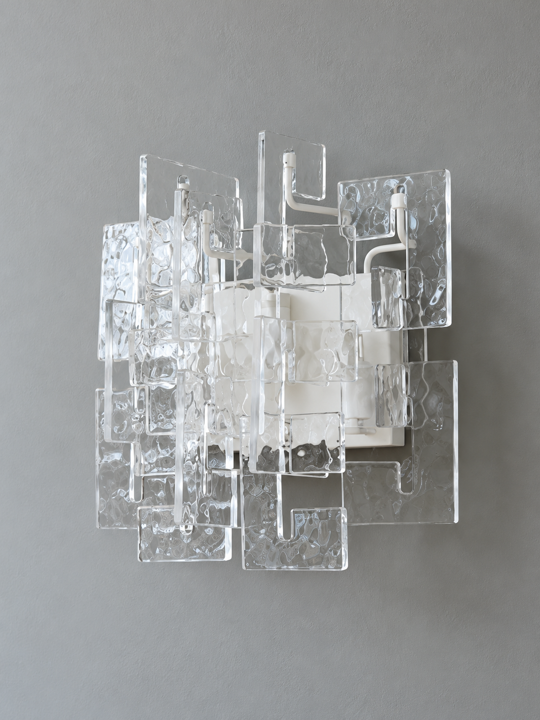 White wall sconce with clear textured glass panels, shown switched off in daylight