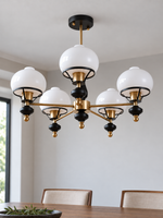 Black and copper-tone 5-light chandelier with white glass shades and ribbed finials, shown switched off