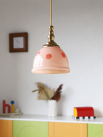 Pink floral glass pendant with copper-tone details in a bedroom-style setting