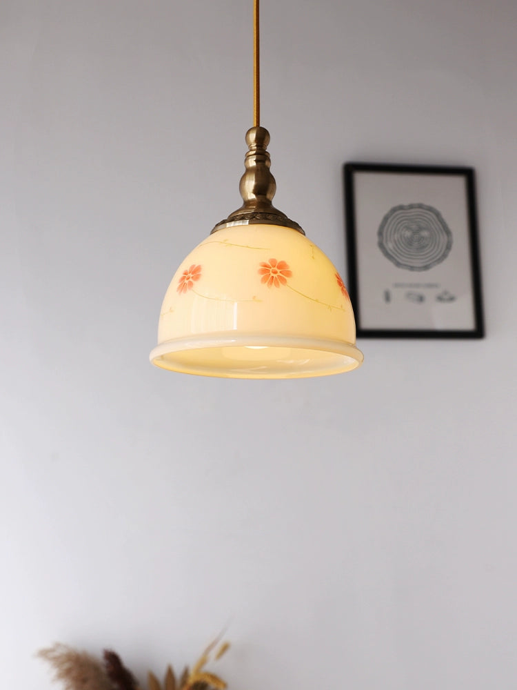 Cream-yellow floral glass pendant illuminated beside framed artwork