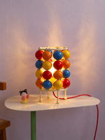 Colorful sphere table lit with cream metal frame and red cord