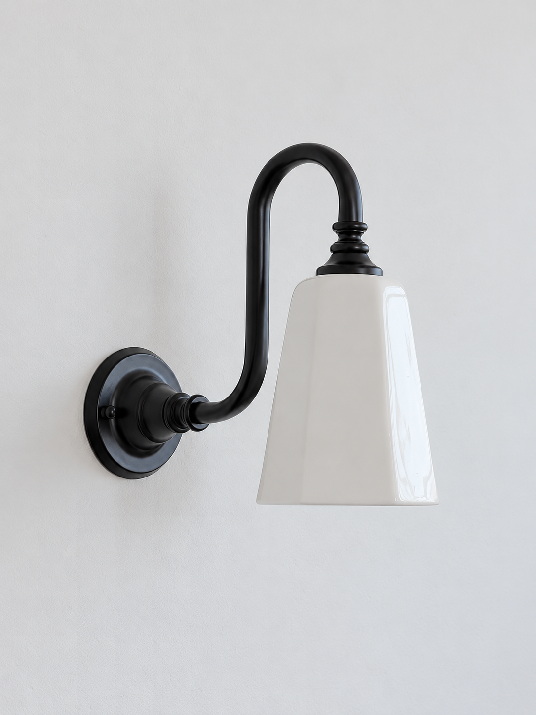 Black bent arm wall sconce with a white ceramic shade, shown unlit
