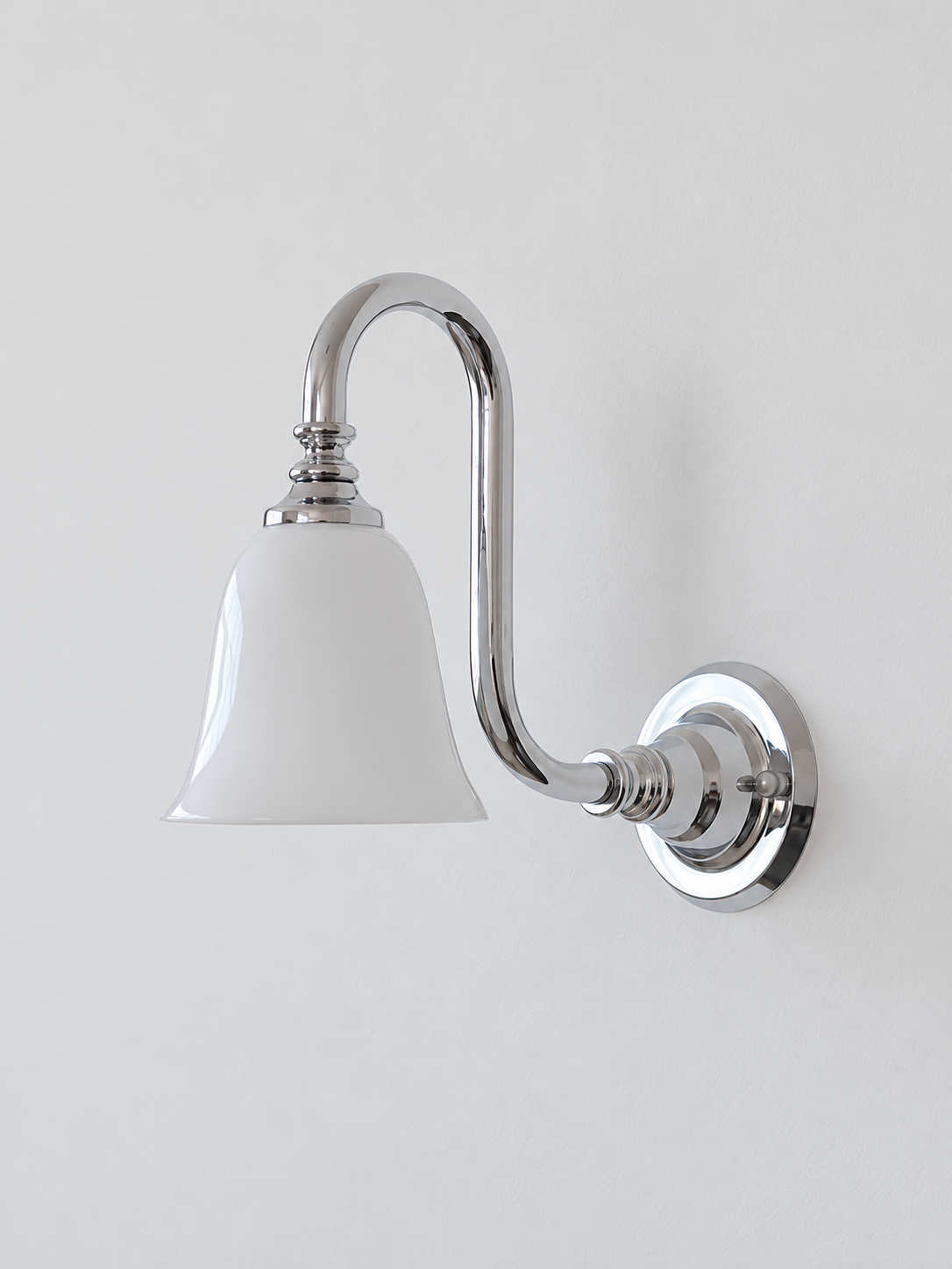 Chrome bent arm wall sconce with a white glass shade, shown unlit