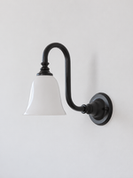 Black bent arm wall sconce with a white glass shade, shown unlit