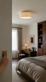 Hand pressing a wall switch beneath the Mercer ceiling light