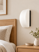 Curved white glass and black wall sconce, bedroom scene