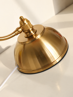 Detailed view of the copper-tone iron dome base, curved arm attachment and white cord