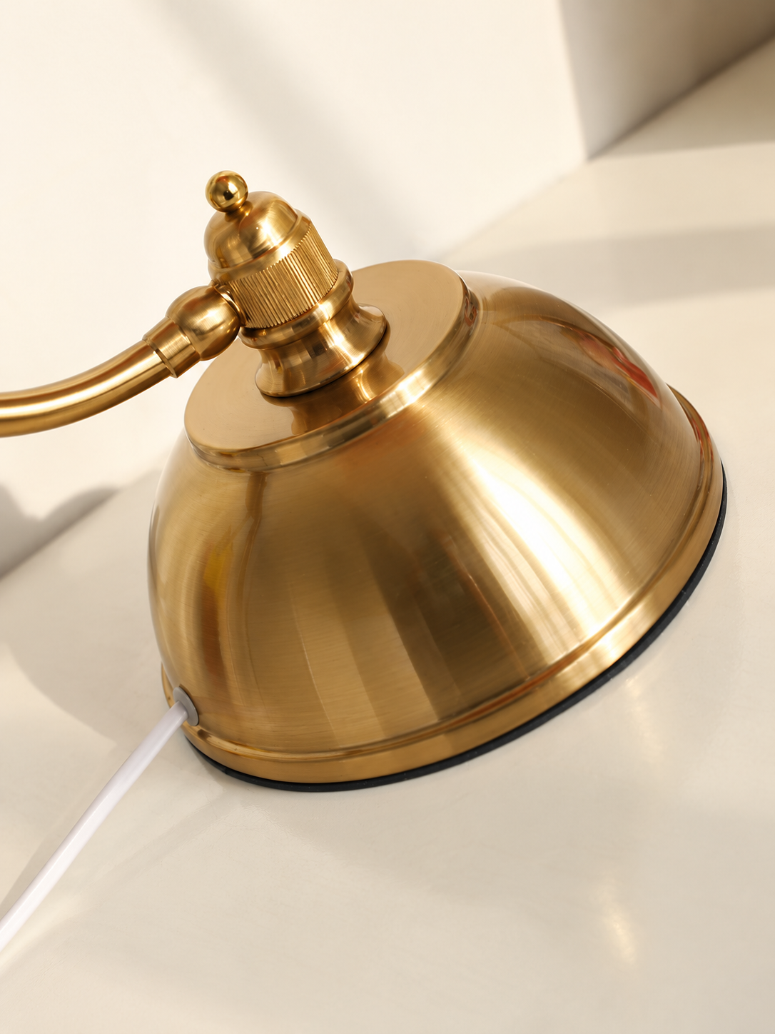 Detailed view of the copper-tone iron dome base, curved arm attachment and white cord