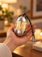 Palm-sized Capsule Glow Portable Lamp held in one hand with its braided carrying cord