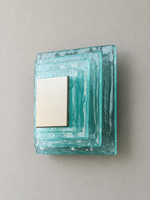 Small wall sconce with blue textured glass and white acrylic insert behind a brushed-metal cover, shown switched off in daylight
