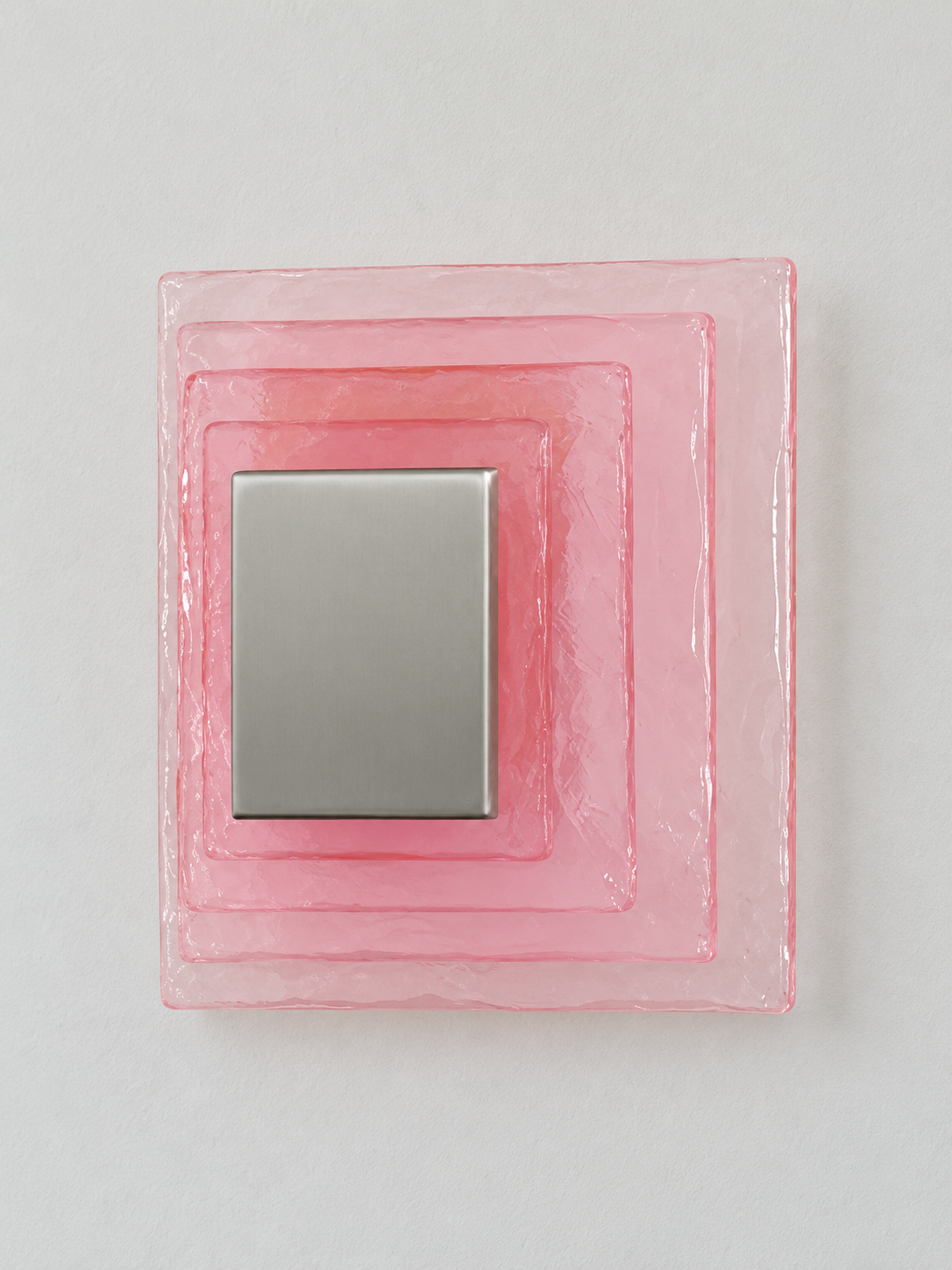 Small wall sconce with pink textured glass and yellow acrylic insert behind a brushed-metal cover, shown switched off in daylight