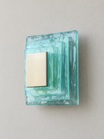 Small wall sconce with blue textured glass and yellow acrylic insert behind a brushed-metal cover, shown switched off in daylight