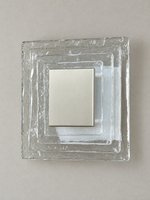 Large wall sconce with clear textured glass and white acrylic insert behind a brushed-metal cover, shown switched off in daylight