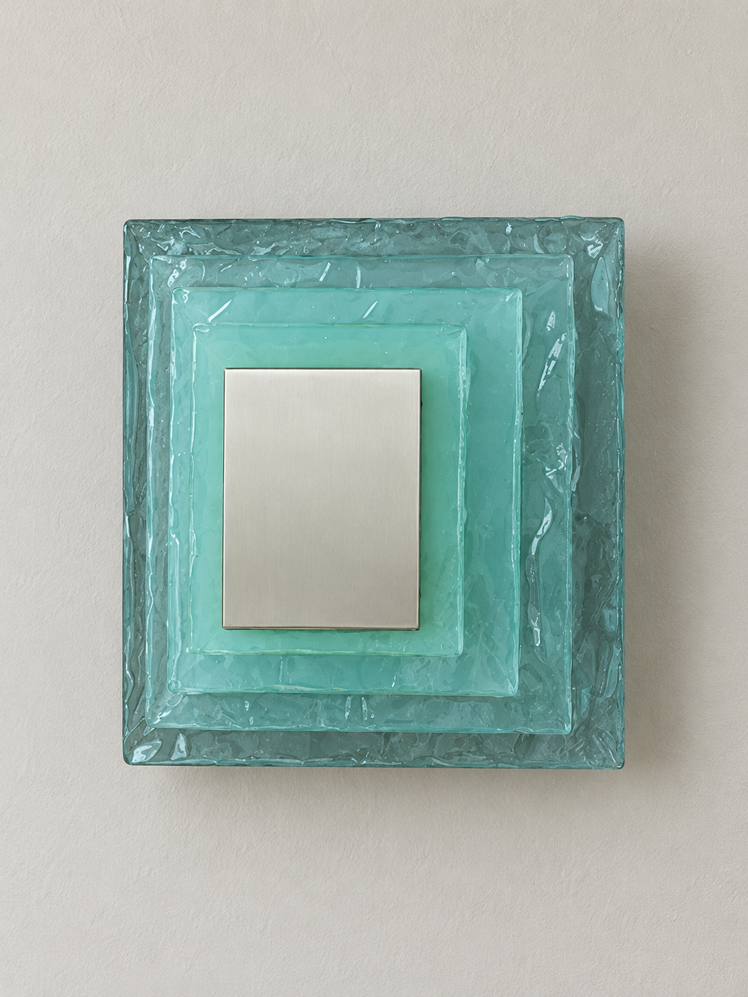 Large wall sconce with blue textured glass and yellow acrylic insert behind a brushed-metal cover, shown switched off in daylight