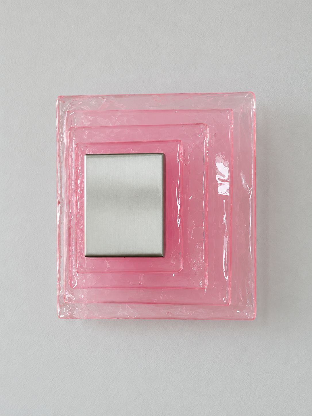 Small wall sconce with pink textured glass and white acrylic insert behind a brushed-metal cover, shown switched off in daylight