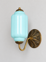 Light Blue ribbed glass wall sconce with copper-tone U-arm and ornate round medallion backplate, shown switched off