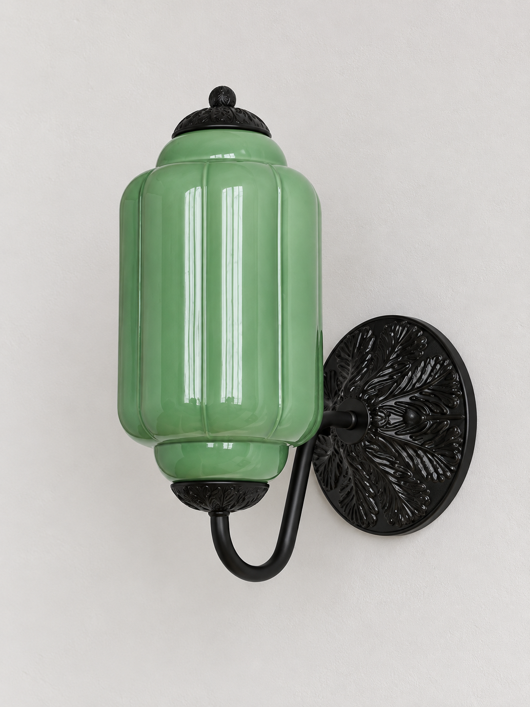 Green ribbed glass wall sconce with black U-arm and ornate round medallion backplate, shown switched off