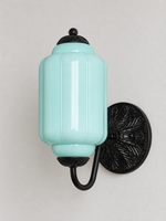 Light Blue ribbed glass wall sconce with black U-arm and ornate round medallion backplate, shown switched off