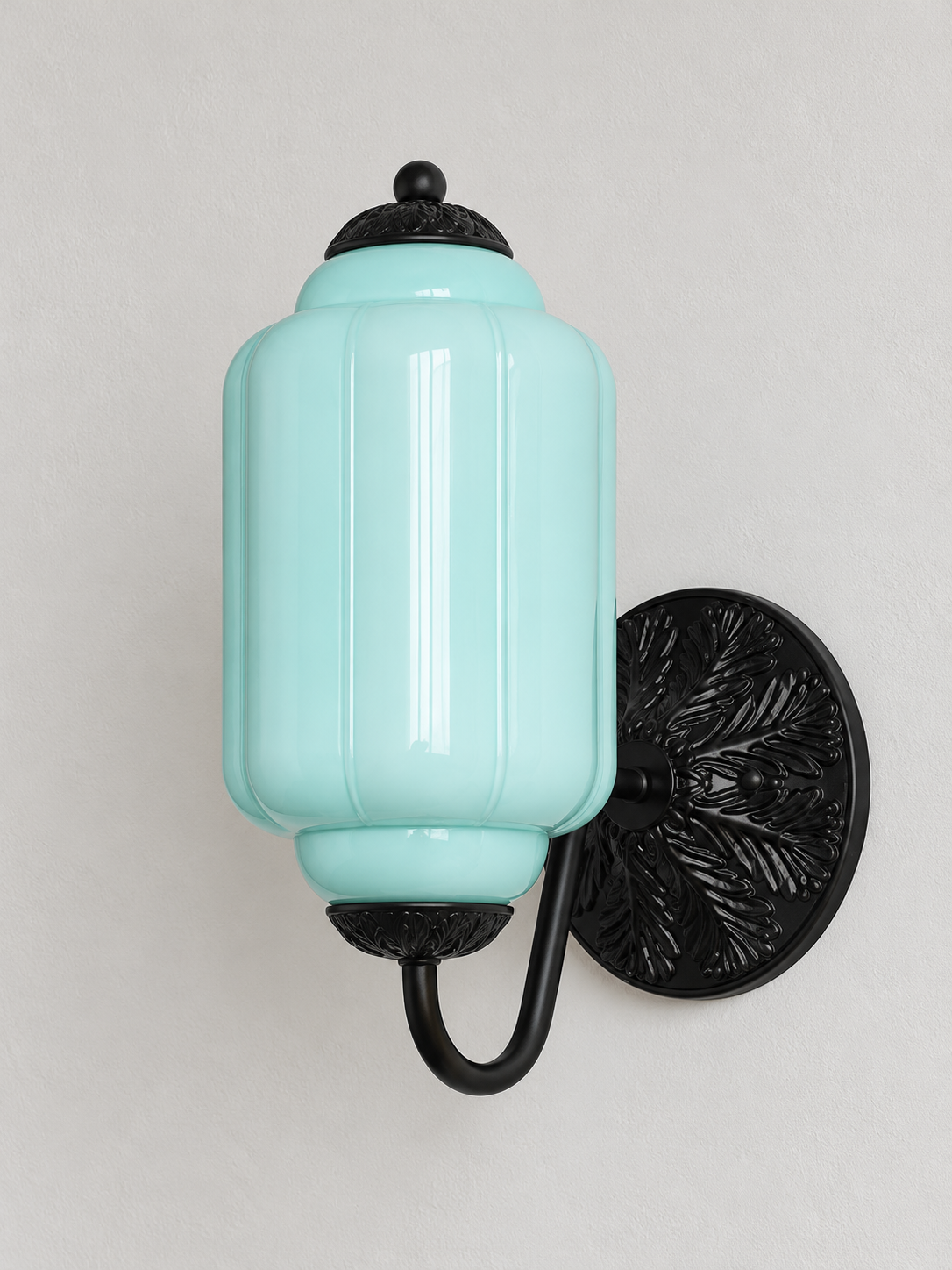 Light Blue ribbed glass wall sconce with black U-arm and ornate round medallion backplate, shown switched off