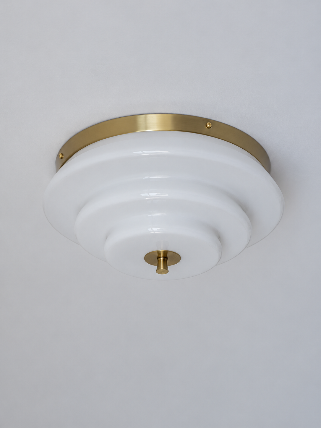 Bronze-tone and white stepped glass ceiling light, switched off against a neutral ceiling