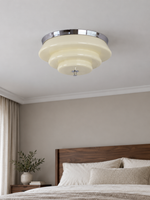 Chrome and cream stepped glass ceiling light, switched off in a daylight bedroom