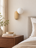 Travertine pill wall light with opal glass globe — bedside scene v1