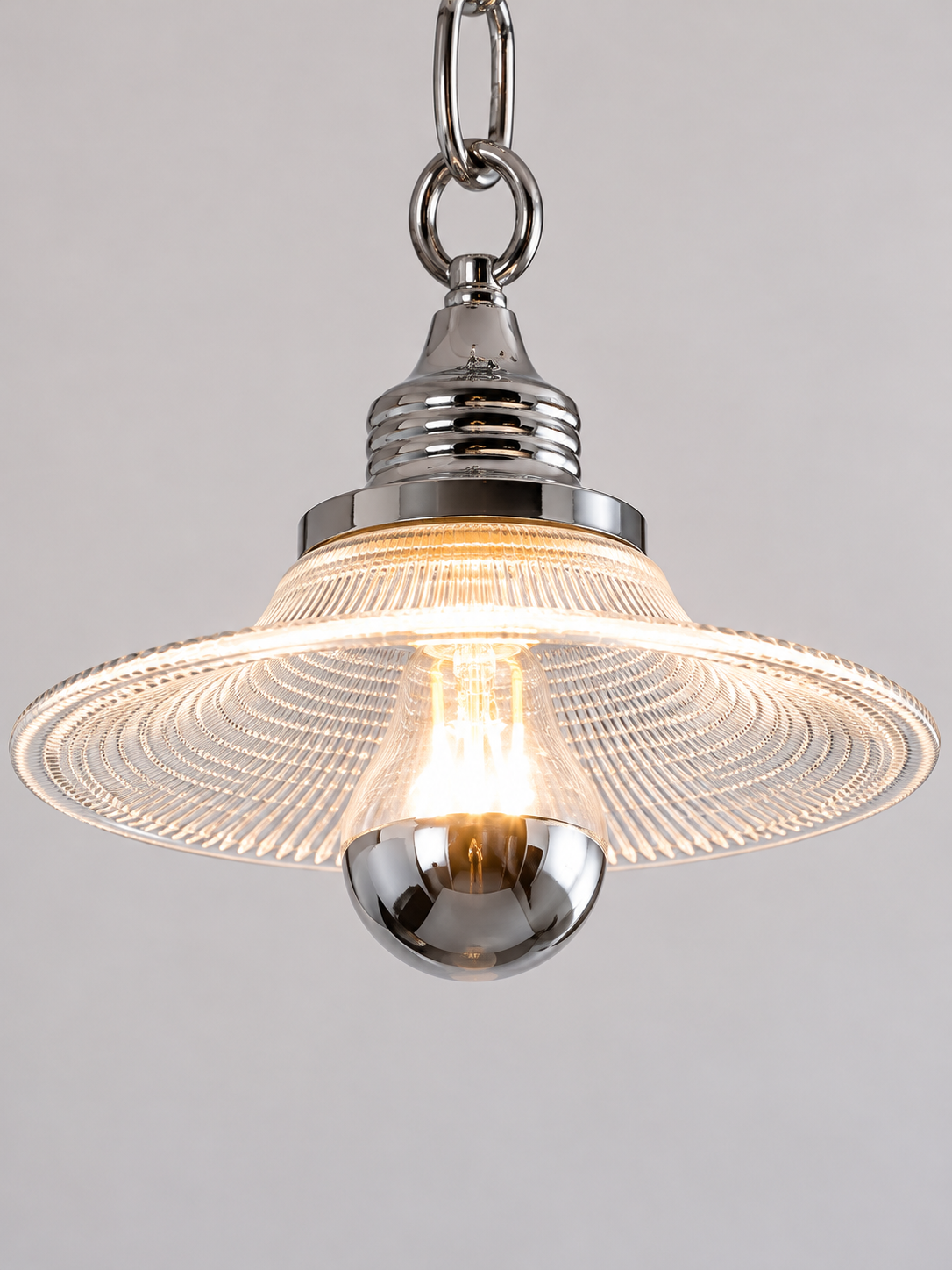 Close-up of chrome socket, prismatic glass shade and half-silvered bulb