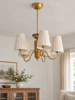 5-light round chandelier in a daylight living room, unlit pleated fabric shades and copper-color hardware