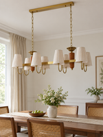 8-light linear chandelier in a daylight dining room, unlit pleated fabric shades and copper-color hardware