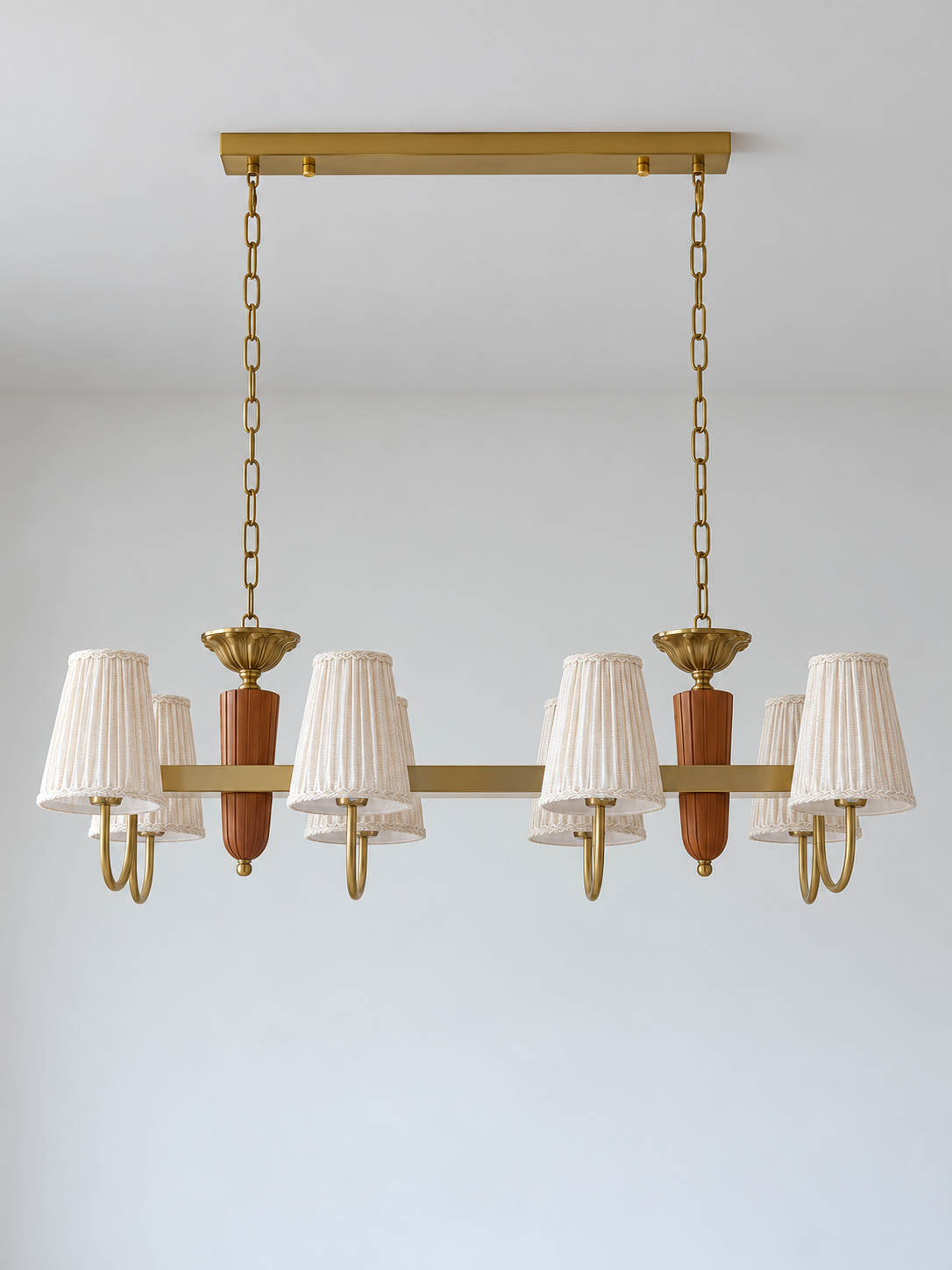 8-light linear chandelier, straight-on product view, unlit pleated fabric shades and copper-color hardware