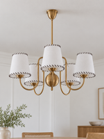 Copper-tone chandelier with 5 white stitched fabric shades, shown unlit, daylight dining-room setting
