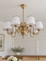 Copper-tone chandelier with 7 white stitched fabric shades, shown unlit, daylight dining-room setting