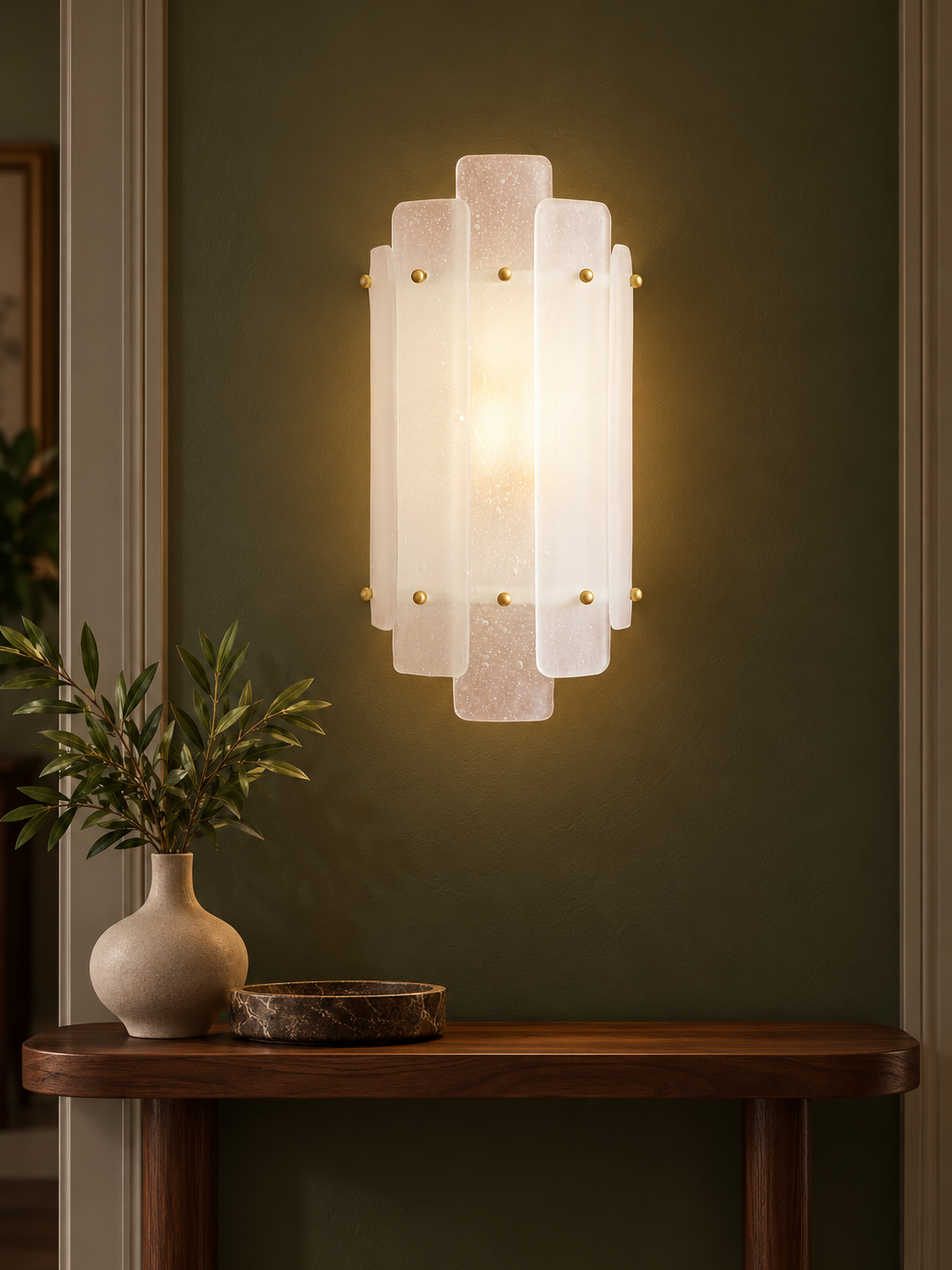 Tiered glass wall sconce in an olive hallway