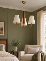 Three-light chandelier in a muted olive bedroom