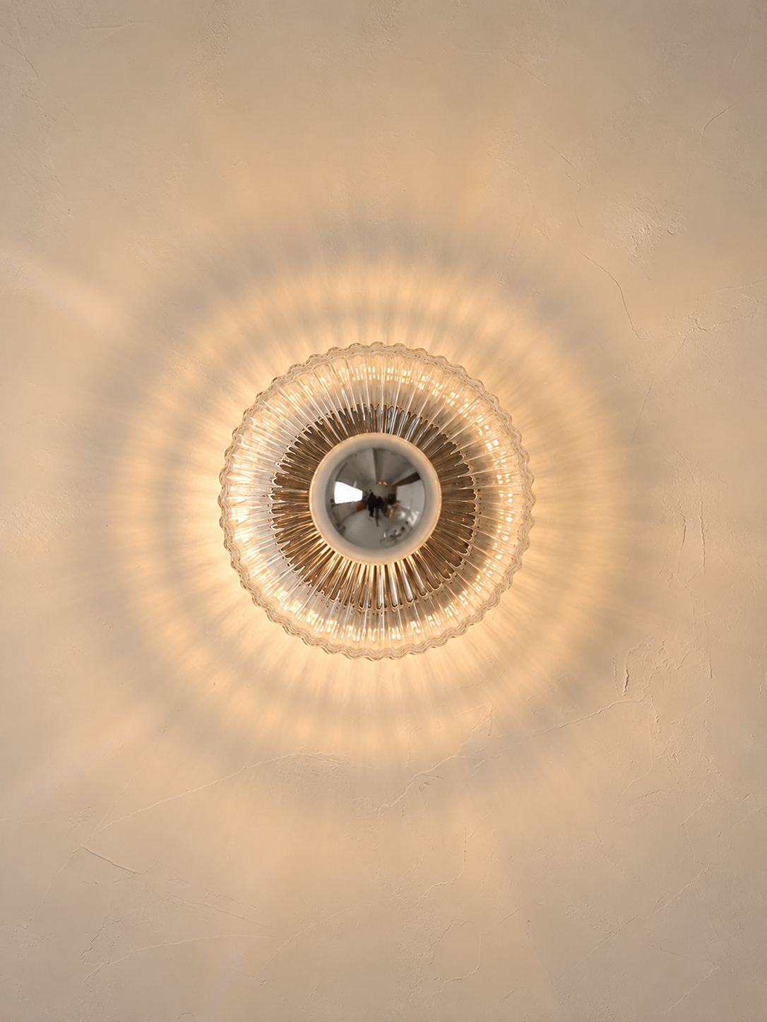 Front view of illuminated radial fluted glass wall light