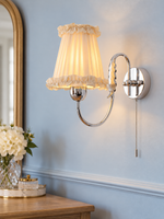 Wheat Scroll fabric wall sconce in Chrome with a pull-cord switch on a pale blue wall