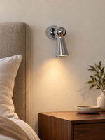 Chrome Cone Wall Spotlight beside a linen headboard