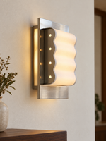 Wave Frame Paper Wall Sconce in Chrome and White, softly illuminated above a walnut console