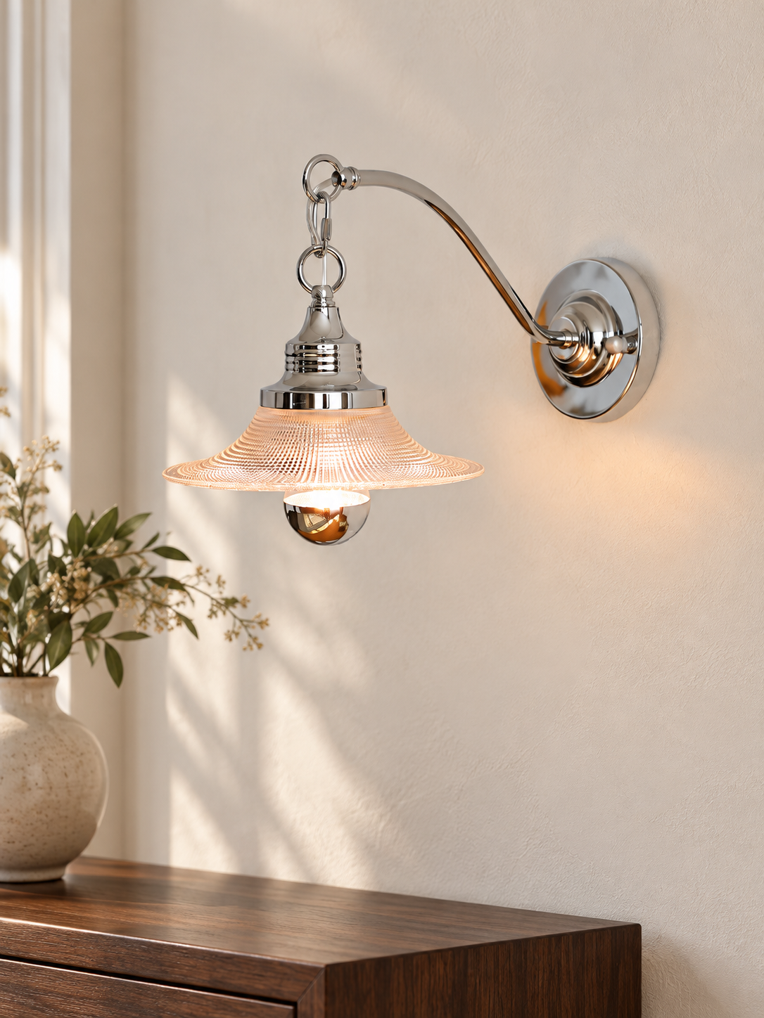 Clear Arc chrome and textured glass wall sconce above a walnut console
