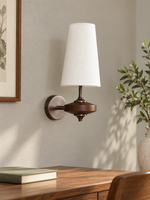 White tapered fabric and wood wall sconce above a writing desk