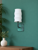 Unlit white fabric wall sconce on a teal wall