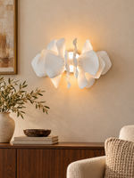 Ceramic Drift white petal wall sconce with soft central light above a walnut console